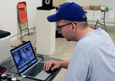 Close up of Mike working on a laptop, surrounded by audio equipment.
