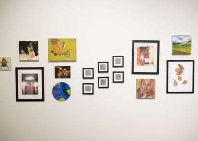 Various artworks from different artists framed on the wall, with a mix of photography and painting.