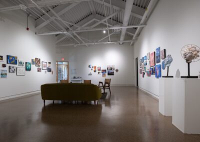 Various artworks for sale on an exhibition hall. There are various paintings, photos and drawings, as well as some sculptures.